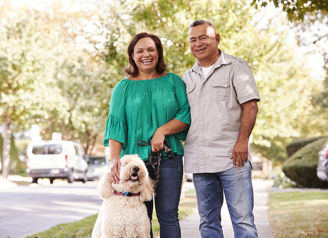 Personal Insurance - Senior Couple Stand on the Sidewalk of Their Neighborhood With Their Large White Dog